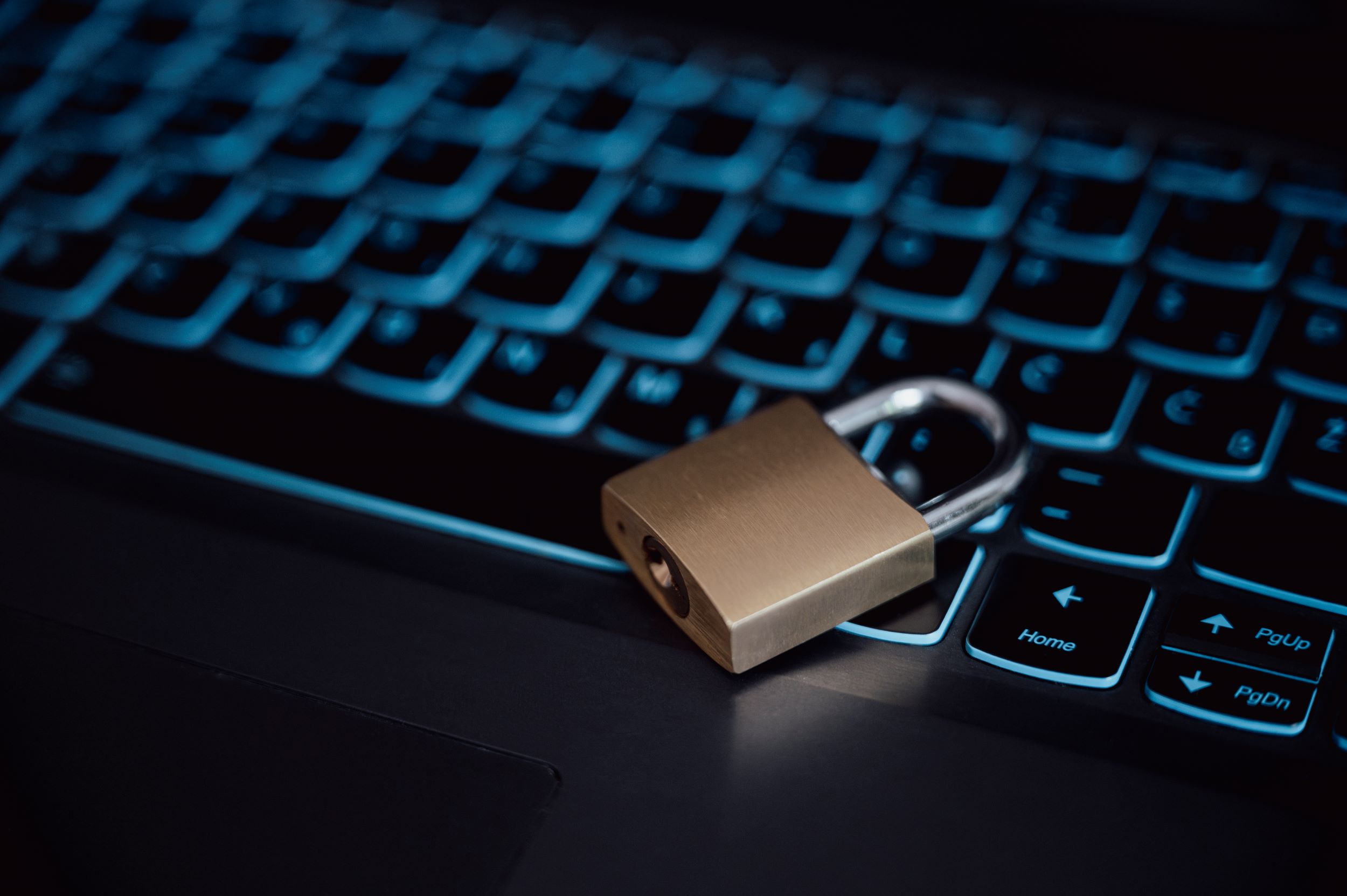 A closed padlock resting on a backlit laptop keyboard, symbolizing data security or cyber safety.