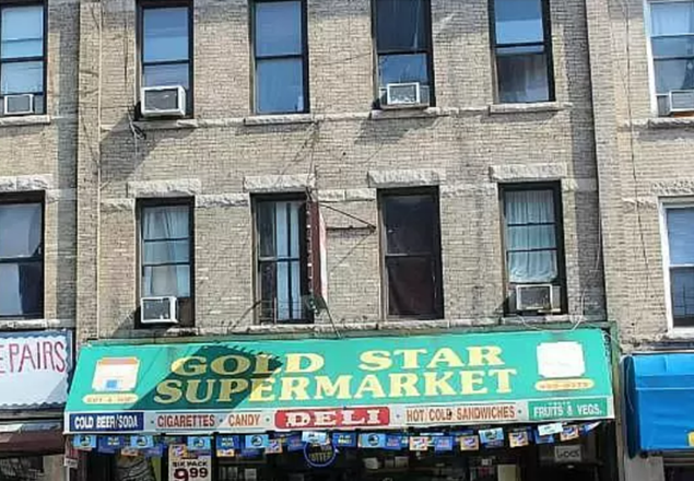 A faded building with a "gold star supermarket" sign displaying ads for deli, sandwiches, and groceries, beneath upper stories with closed, weathered windows.