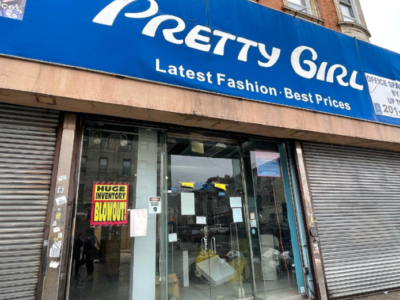 Front view of a clothing store named "pretty girl" with signs advertising the latest fashion and best prices. the store has a large "huge inventory blowout" sale sign on the door.