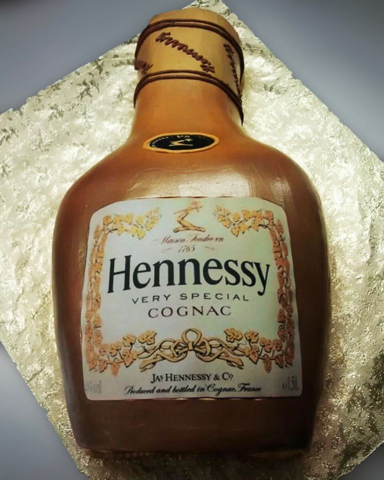 A bottle of hennessy very special cognac with intricate label details, presented on a silvery textured surface. the distinctive shape and branding are clear.