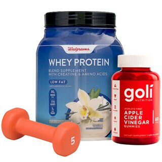 A walgreens whey protein container, a dumbbell, and a bottle of goli apple cider vinegar gummies arranged on a plain background.