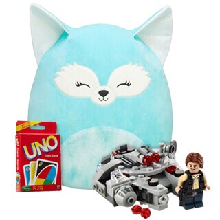 A plush blue cat-shaped pillow with closed eyes, a box of uno cards, and a lego star wars set featuring a small spaceship and a minifigure.