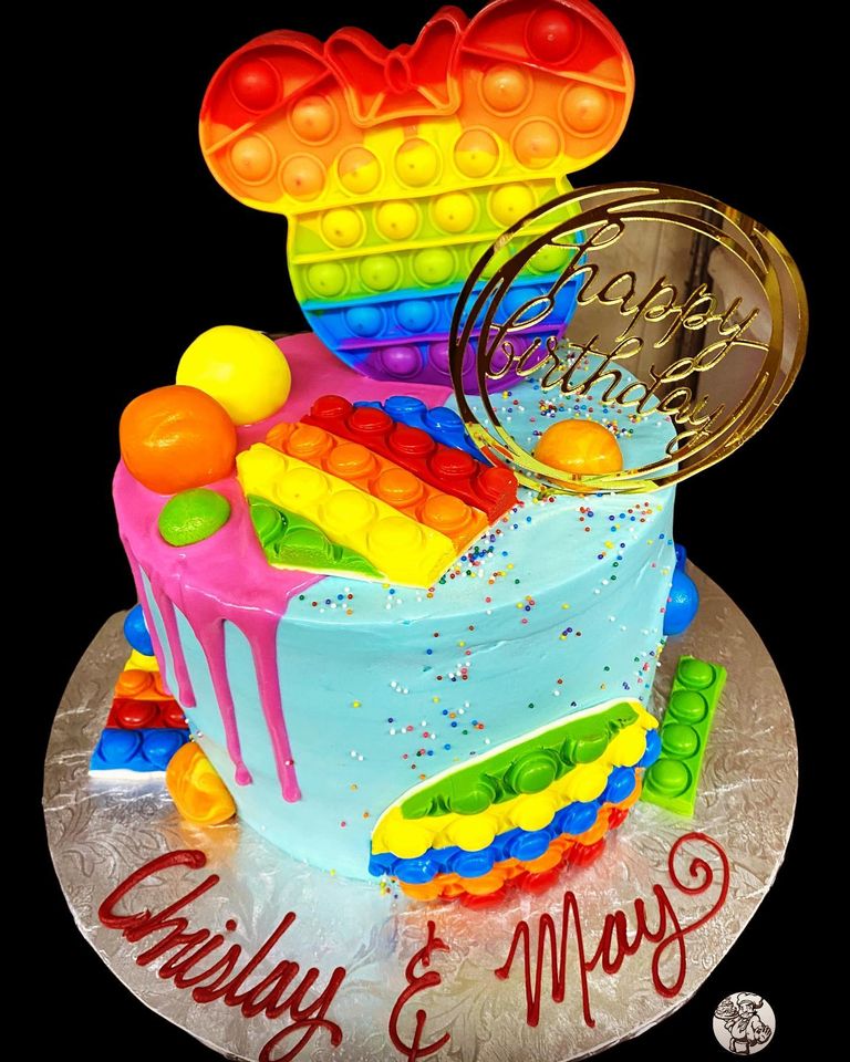A colorful birthday cake inspired by lego and mickey mouse, featuring a multi-layer design with lego bricks, topped with a mickey silhouette and a "happy birthday" plaque.