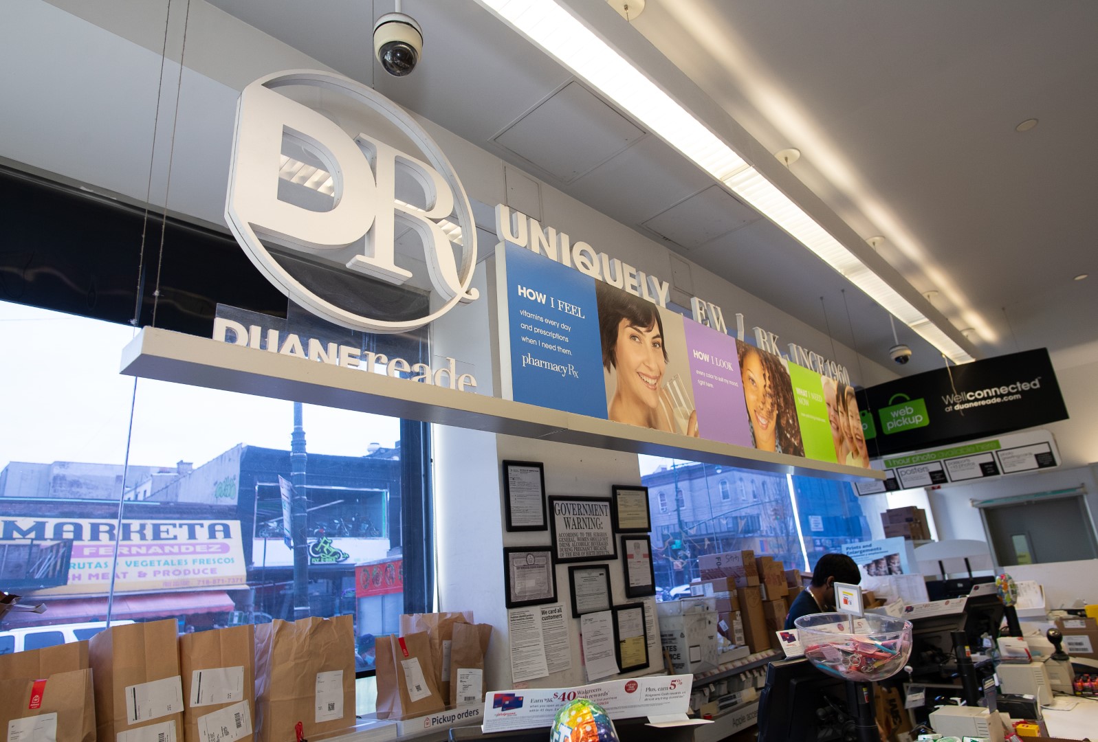 Interior view of a duane reade store showing promotional banners, a visible logo, and a checkout with several paper bags on the counter.