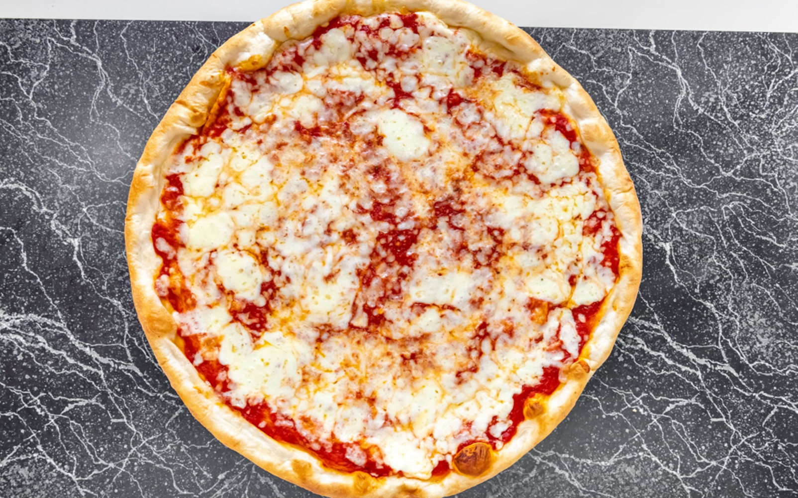A freshly baked cheese pizza with a golden crust on a marble surface.