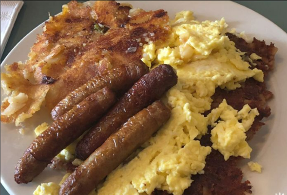 A hearty breakfast plate featuring scrambled eggs, crispy bacon strips, sausage links, and golden-brown hash browns.